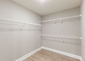 Thumbnail 23 of 53 - an empty closet with white shelves and a wood floor