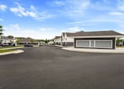 Thumbnail 30 of 36 - A large, modern building with a grey roof and a parking lot in front.
