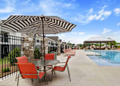 Thumbnail 23 of 36 - A patio with a table and chairs is set up next to a pool.