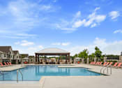 Thumbnail 20 of 36 - A swimming pool surrounded by red chairs and a gazebo.