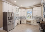 Thumbnail 15 of 36 - A kitchen with a stainless steel refrigerator and white cabinets.
