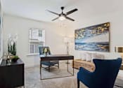 Thumbnail 5 of 36 - A blue chair sits in a room with a ceiling fan and a painting on the wall.