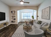 Thumbnail 9 of 60 - A living room with a grey sofa, a wooden coffee table, and a television on the wall.