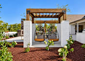 Thumbnail 25 of 29 - A white house with a wooden pergola and a swing hanging from it.