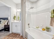 Thumbnail 18 of 36 - A bathroom with a white tub and a white shower curtain.