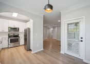 Thumbnail 47 of 59 - a renovated kitchen and living room with white cabinets and a door to a hallway