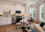Thumbnail 32 of 40 - A modern kitchen with white cabinets and a dining area with a round table and chairs.