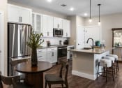 Thumbnail 70 of 94 - a kitchen with white cabinets and a table with chairs