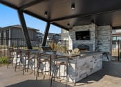 Thumbnail 41 of 94 - a covered patio with a stone fireplace and bar