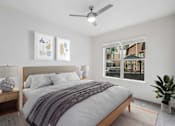 Thumbnail 11 of 57 - Decatur, GA, Apartments Near Emory Hospital - Arlo - Bedroom With Wood Framed Bed, Gray Bedding, Matching Nightstands With Lamps, Ceiling Fan, And Large Window Overlooking An Outdoor Patio.