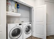 Thumbnail 20 of 57 - A white door is open to reveal a laundry room with a washer and dryer.