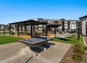 Thumbnail 50 of 94 - a picnic area with a table and hammocks in front of an apartment building
