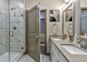 Thumbnail 17 of 25 - a bathroom with a shower and a sink and a mirror