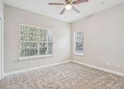 Thumbnail 29 of 36 - A room with a ceiling fan and two windows.