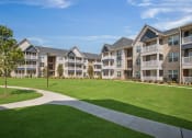 Thumbnail 46 of 49 - an exterior view of an apartment complex with a large green lawn