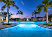 Thumbnail 57 of 78 - A swimming pool surrounded by palm trees at dusk.