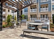 Thumbnail 40 of 49 - an outdoor patio with tables and benches at the bradley braddock road station apartments
