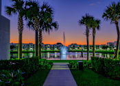 Thumbnail 56 of 78 - A beautiful fountain surrounded by palm trees and buildings in the background.