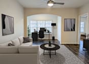 Thumbnail 10 of 60 - A living room with a beige couch, a black coffee table, and a ceiling fan.