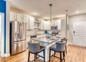 Thumbnail 1 of 34 - 3 BR Apartments in Maitland, FL - Parker at Maitland Station - Modern Kitchen with Wood Vinyl Plank Flooring, Large Cooking Island with Stool Seating, Pendant Light, Granite Countertops, White Shaker-Style Cabinetry, Stainless Steel Appliances, and White Subway Tile Backsplash