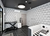 Thumbnail 36 of 94 - A bathroom with a white tub and a black and white tiled wall.