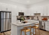 Thumbnail 3 of 46 - a kitchen with a large island with two stools in front of it
