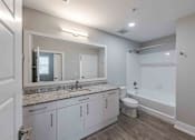 Thumbnail 20 of 37 - A bathroom with a sink, mirror, toilet, and bathtub.