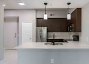 Thumbnail 14 of 37 - A modern kitchen with a white countertop and stainless steel appliances.