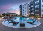 Thumbnail 2 of 25 - an apartment swimming pool with chairs at dusk