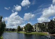 Thumbnail 29 of 31 - A large building is situated by a lake with a fountain in front of it.