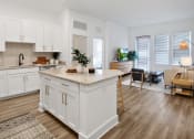 Thumbnail 4 of 46 - a kitchen and living room with white cabinets and a granite counter top