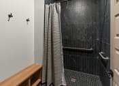 Thumbnail 27 of 94 - a bathroom with a black tiled shower and a shower curtain
