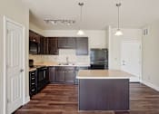 Thumbnail 29 of 42 - A kitchen with dark wood cabinets and a white island.