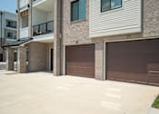 Thumbnail 38 of 43 - A building with brown garage doors and a balcony.