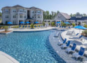Thumbnail 14 of 54 - a swimming pool with chairs and umbrellas in front of an apartment building