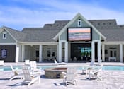 Thumbnail 72 of 72 - A poolside area with white chairs and a building in the background.