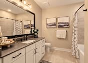 Thumbnail 7 of 29 - A bathroom with a large mirror, a sink, a toilet, and a shower curtain.