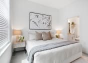 Thumbnail 9 of 46 - Apartments Norcross, GA for Rent - The Darnell - Bedroom with Carpeted Floor, White Walls, Bed, Nightstands with Lamps, Wall Art, and Private Bathroom