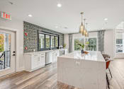 Thumbnail 4 of 36 - A kitchen with a white island and a chandelier.