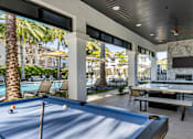 Thumbnail 44 of 53 - A pool table is in the middle of a patio with a TV and a fireplace.
