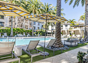 Thumbnail 36 of 53 - A poolside area with lounge chairs and umbrellas.