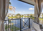 Thumbnail 46 of 53 - A balcony with a chair and a view of a lake and houses.