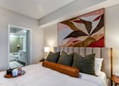 Thumbnail 28 of 53 - A bedroom with a large bed and a painting on the wall.