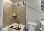 Thumbnail 30 of 53 - A bathroom with a white toilet and a tiled shower.