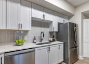 Thumbnail 22 of 53 - A kitchen with white cabinets and a stainless steel refrigerator.