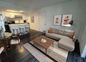 Thumbnail 7 of 28 - A modern living room with a grey couch and a wooden coffee table.