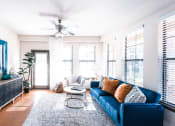 Thumbnail 16 of 36 - a living room with a blue couch and a ceiling fan