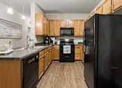 Thumbnail 4 of 38 - A black refrigerator is in the corner of a kitchen with wooden cabinets.
