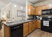 Thumbnail 3 of 38 - A kitchen with wooden cabinets and black appliances.