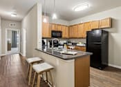 Thumbnail 2 of 38 - A kitchen with wooden cabinets and a black refrigerator.
